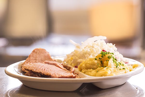 Ein Teller mit Fleisch, Sauerkraut und Kartoffelp&uuml;ree.