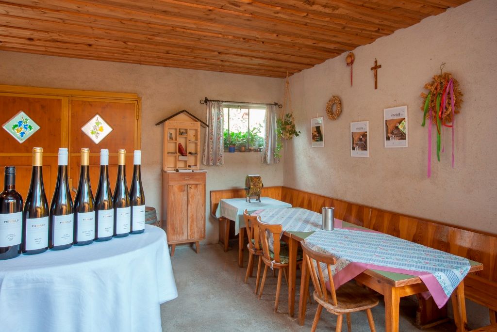 Verkostungsraum im Weingut Piewald mit Weinflaschen auf einem Tisch und rustikaler Einrichtung.