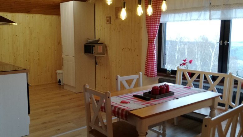 Gem&uuml;tliches Dachgeschoss-Apartment mit Holzw&auml;nden, Esstisch und H&auml;ngelampen.