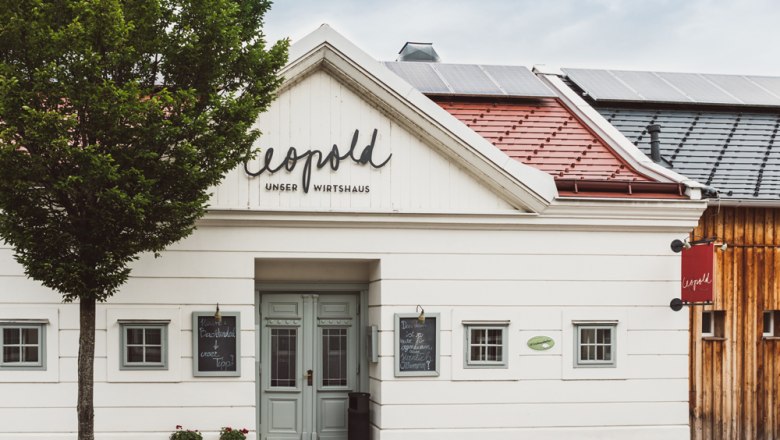 Traditionelles Wirtshaus mit Holzfassade und Solarpanelen auf dem Dach.