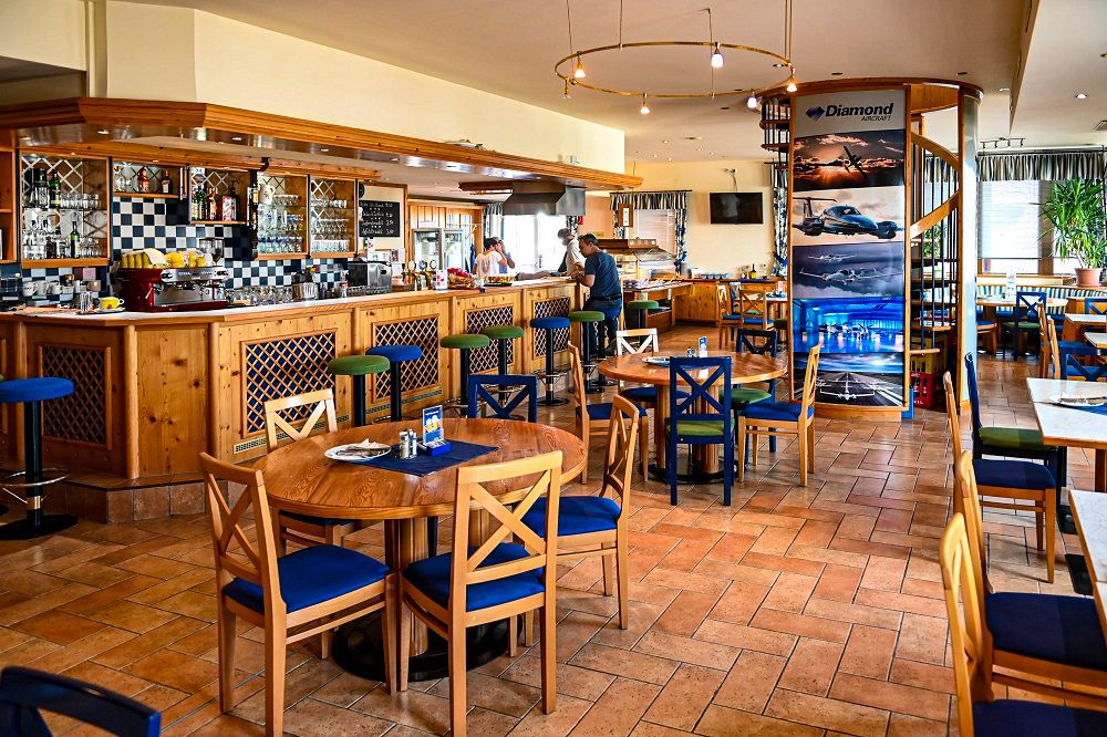 Innenansicht eines gemütlichen Lokals mit Holzmöbeln und Barbereich.