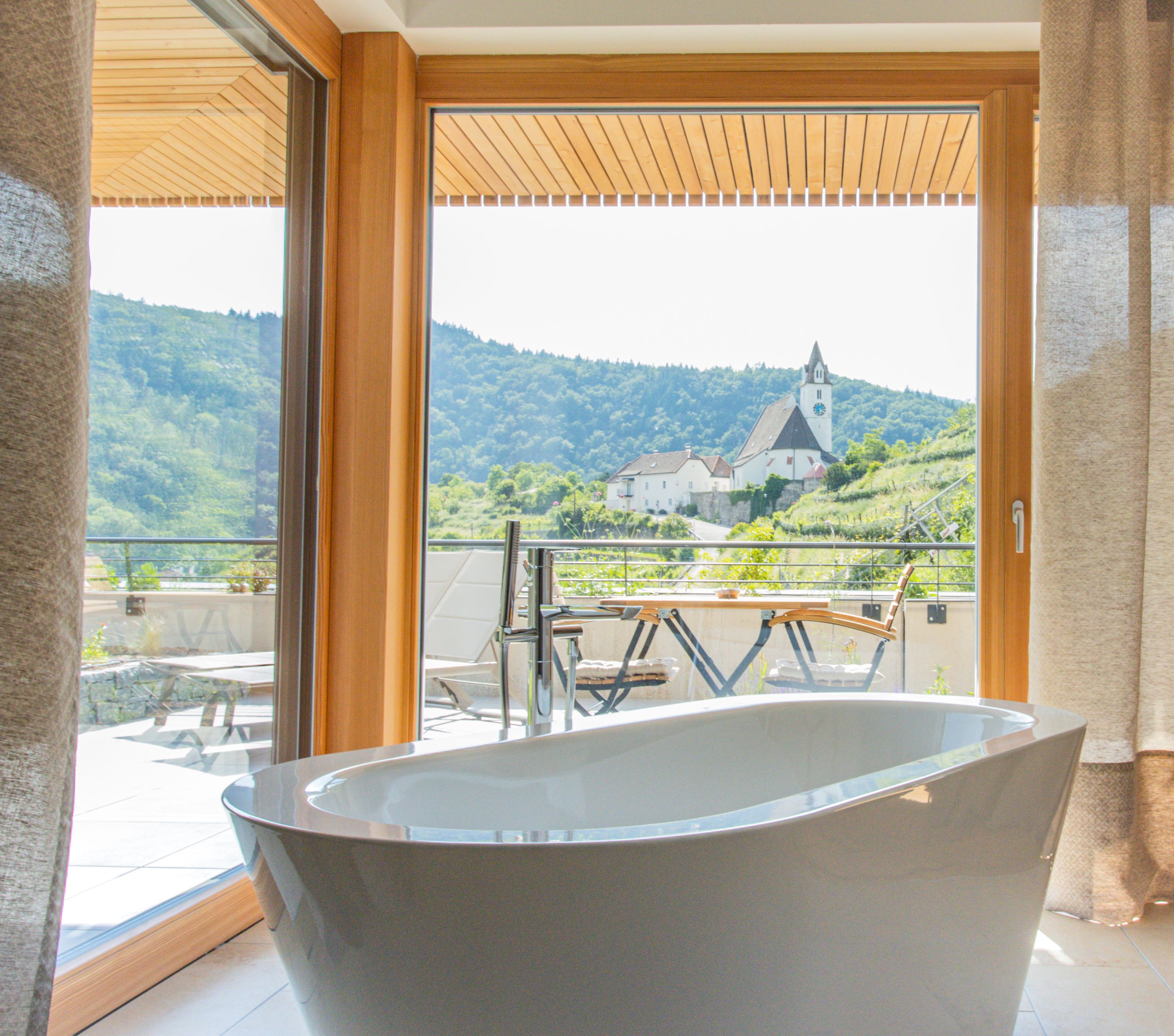 Luftaufnahme eines modernen Hotels mit Terrassen und begrünten Dächern, umgeben von Weinbergen.