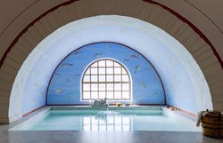 Römerstadt Carnuntum mit rekonstruierten Gebäuden und roten Dächern, umgeben von grünen Bäumen und Rasenflächen.