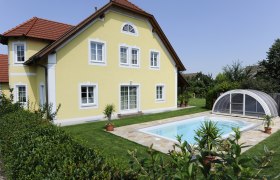 Gelbes Gästehaus mit rotem Dach und Pool im Garten.