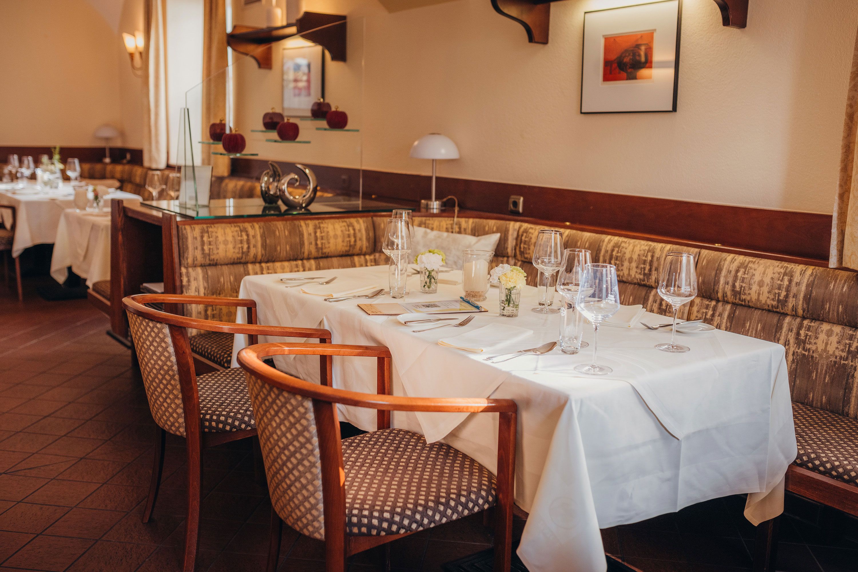 Elegantes Restaurant mit gedecktem Tisch, weißen Tischdecken und stilvollen Stühlen.