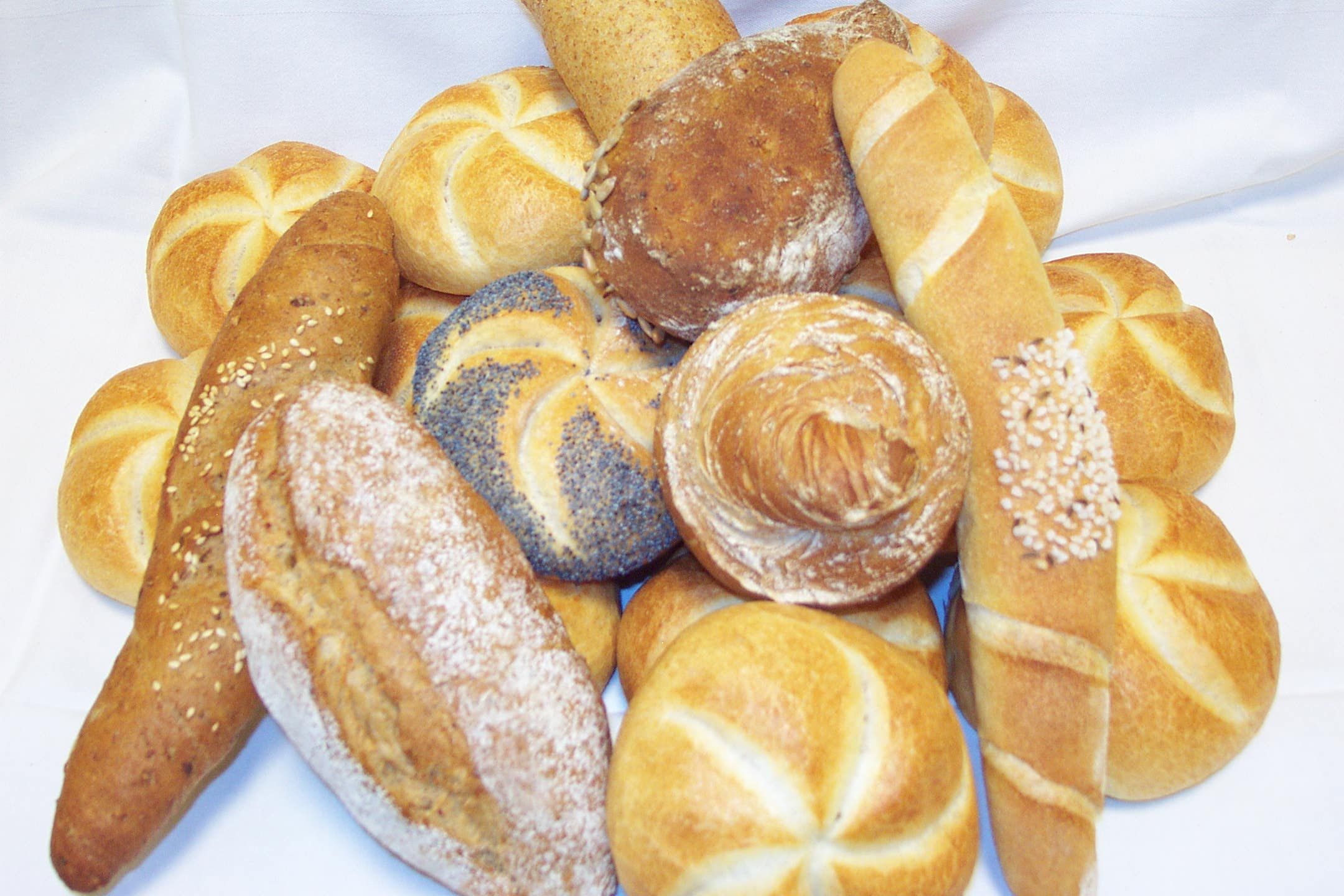 Verschiedene Brötchen und Brote auf einem weißen Tuch arrangiert.