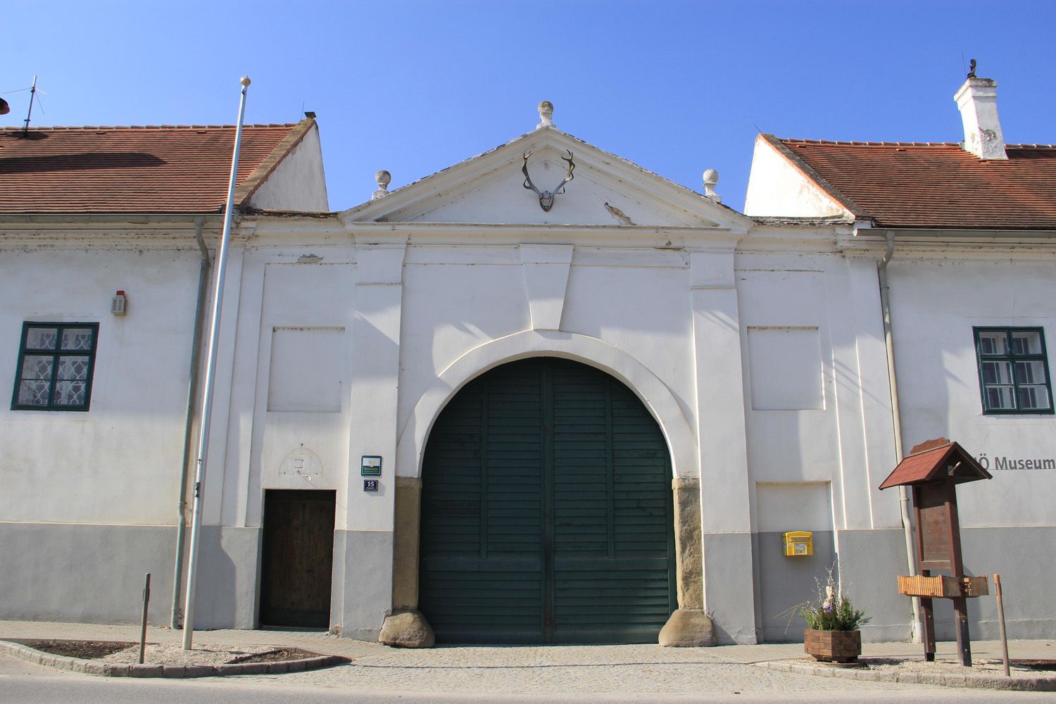 Historisches Gebäude mit großem Tor und Hirschgeweih an der Fassade.
