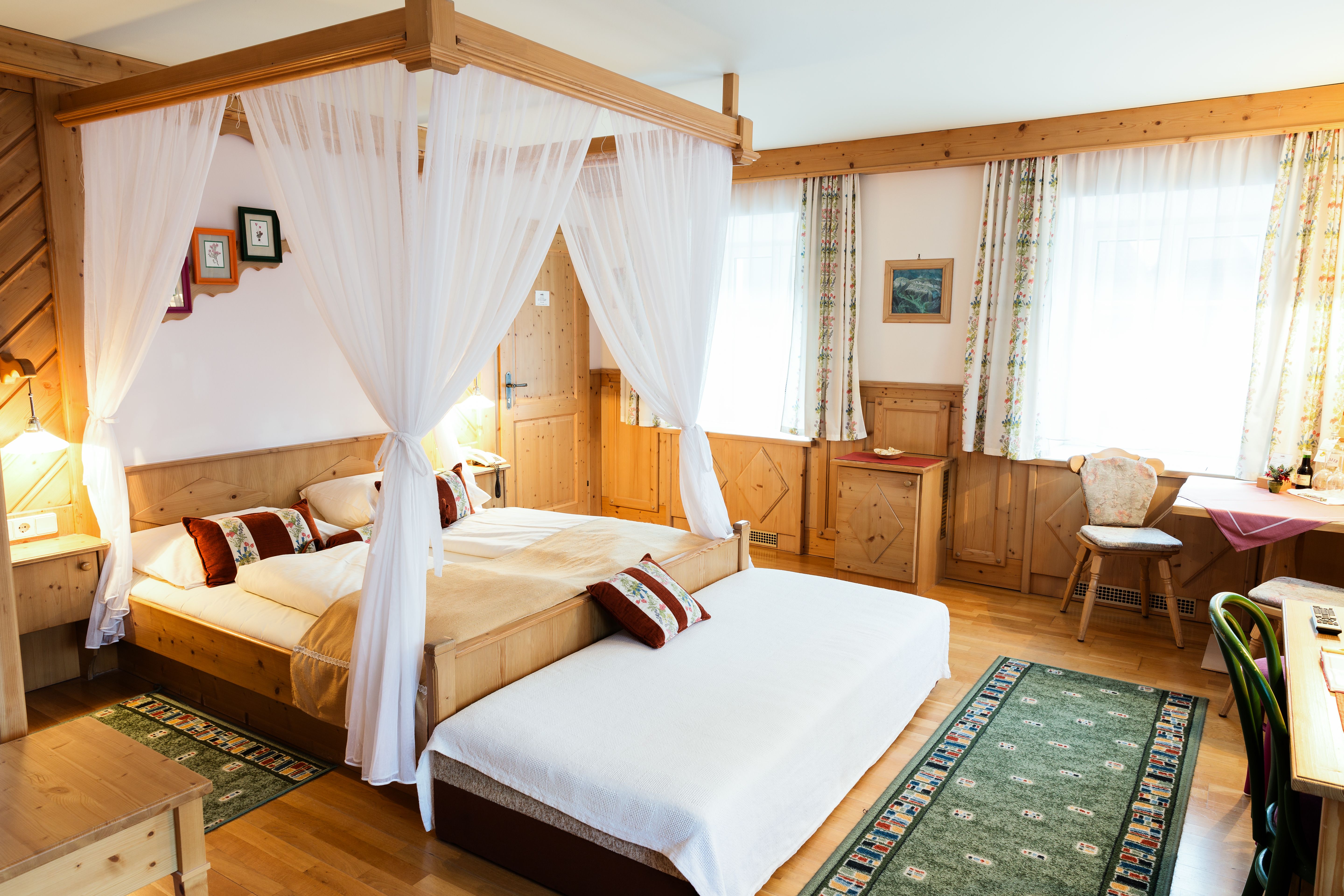 Gemütliches Hotelzimmer mit Himmelbett, Holzmöbeln und Teppichen.