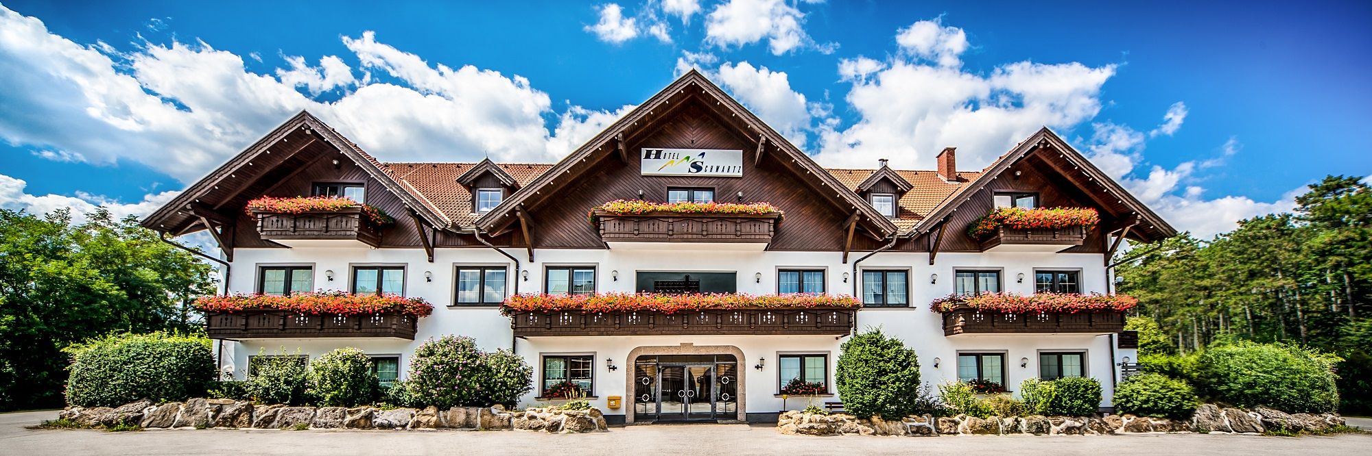 Ein traditionelles Hotel mit Holzbalkonen und Blumenkästen vor einem blauen Himmel.