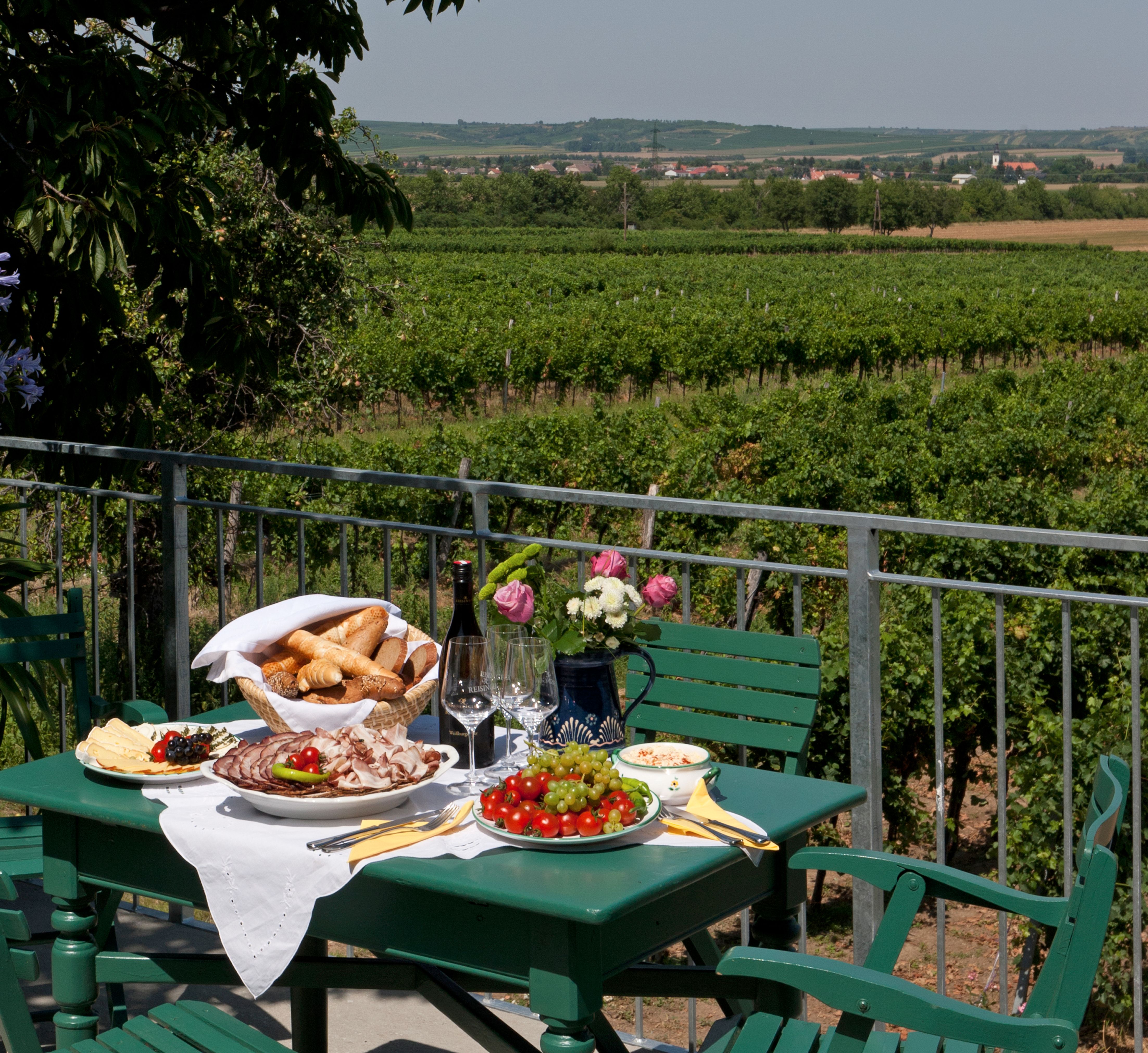 Ein gedeckter Tisch auf einer Terrasse mit Blick auf Weinberge.