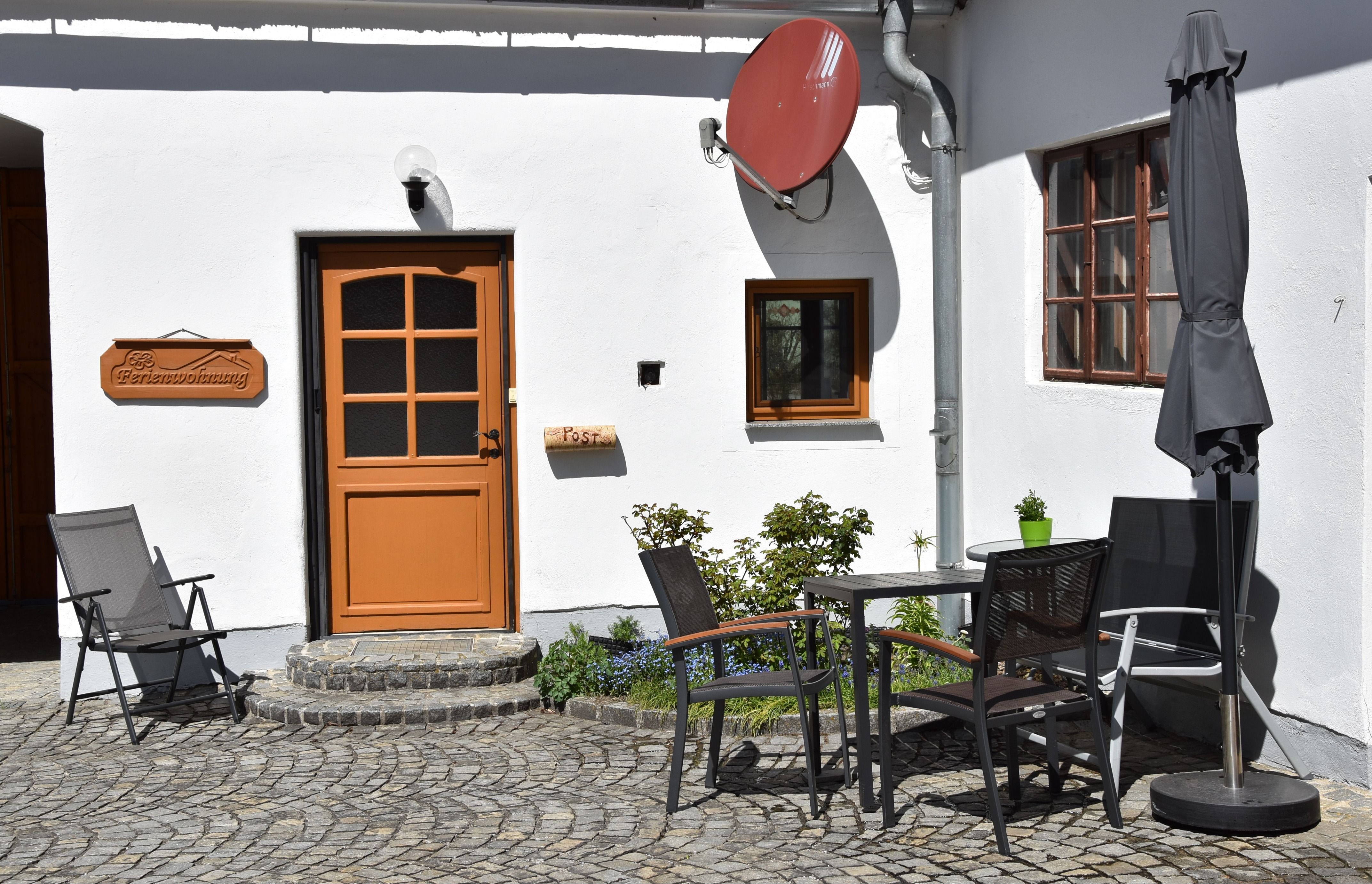Innenhof mit Sitzgelegenheit mit Tisch, Stühlen und Sonnenschirm.