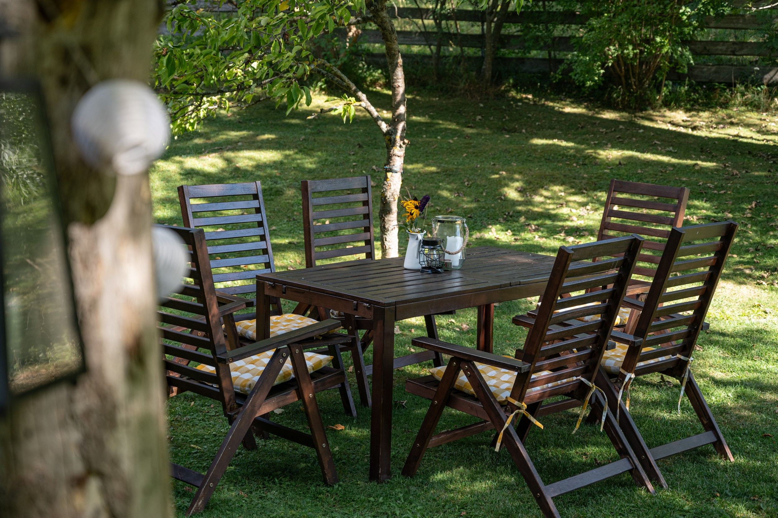 Garten mit Holztisch und Stühlen, dekoriert mit Blumen und Kerzen.