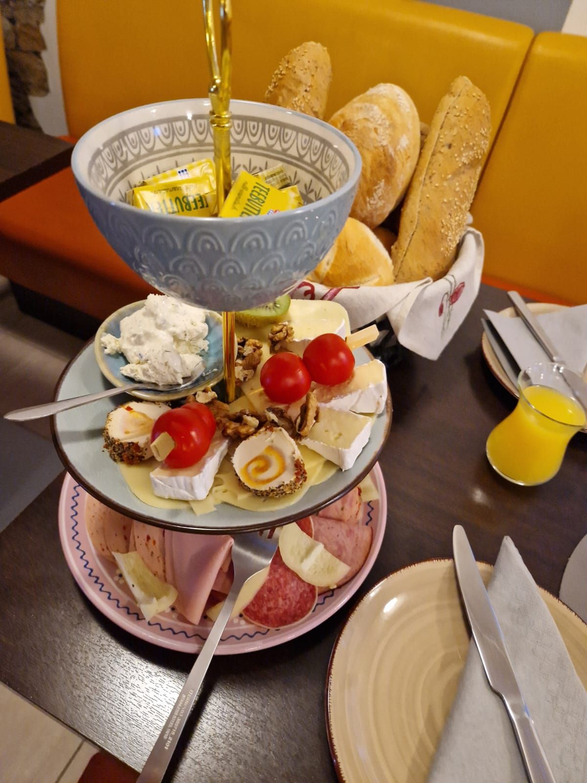 Frühstücksetagere mit Aufschnitt, Käse, Brötchen und Butter im Café.
