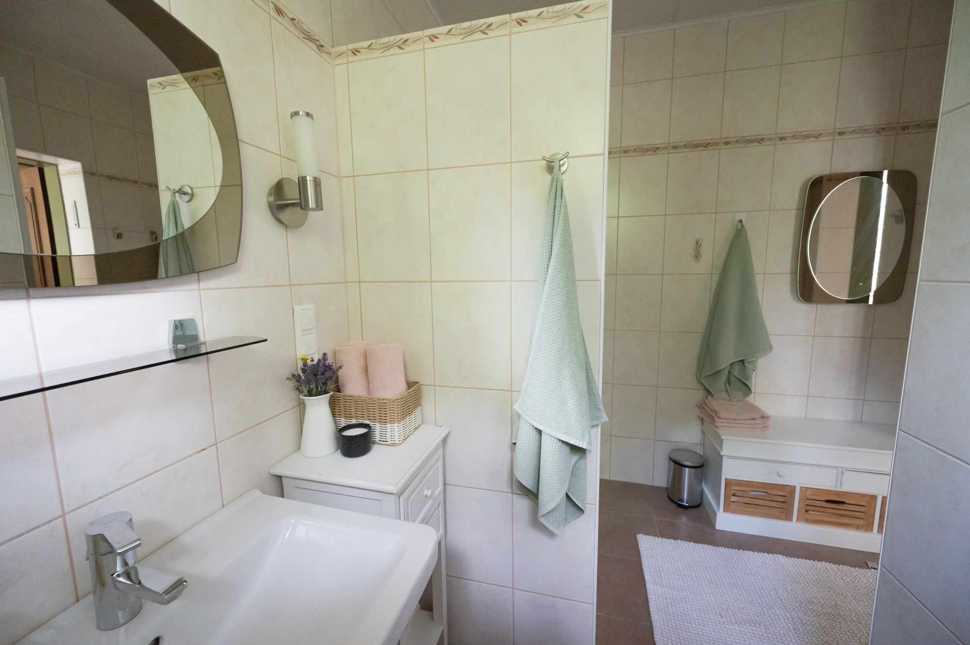 Modernes Badezimmer mit Waschbecken, Spiegel, Handtüchern und Dekoration.