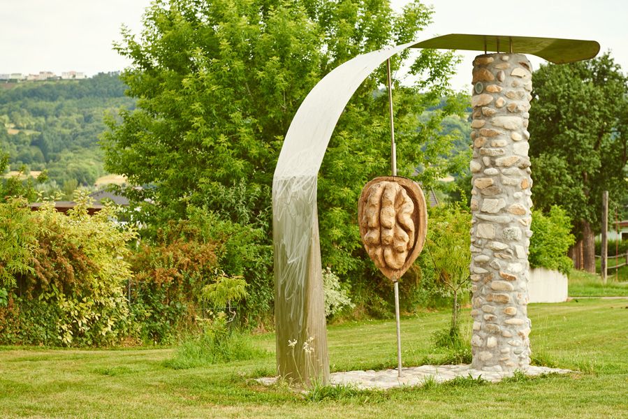 Skulptur einer Walnuss in Krummnußbaum, umgeben von Bäumen und Wiese.