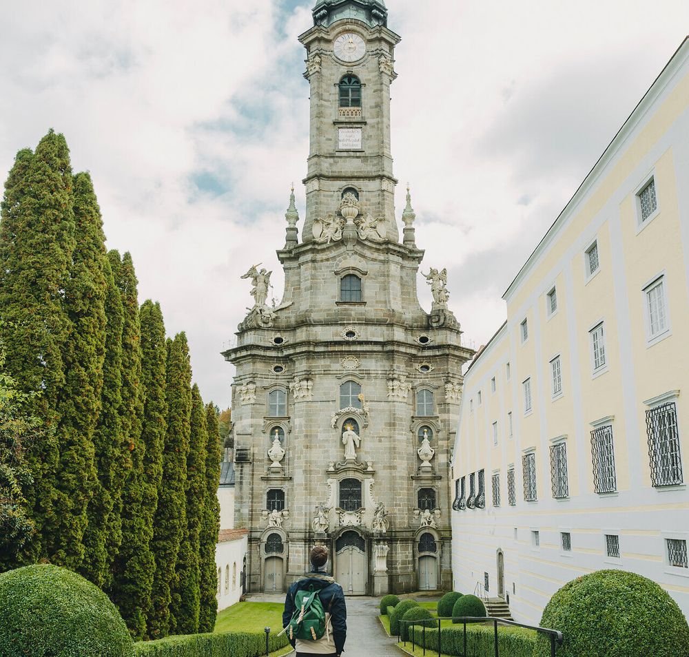 Die majestätische Architektur des Stifts Zwettl erhebt sich stolz gegen den herbstlichen Himmel, während die grünen Hecken und Bäume eine einladende Atmosphäre schaffen. Ein Spaziergang entlang des gepflegten Weges verspricht nicht nur atemberaubende Ausblicke, sondern auch eine tiefere Verbindung zur Geschichte und Kultur dieser beeindruckenden Stätte.