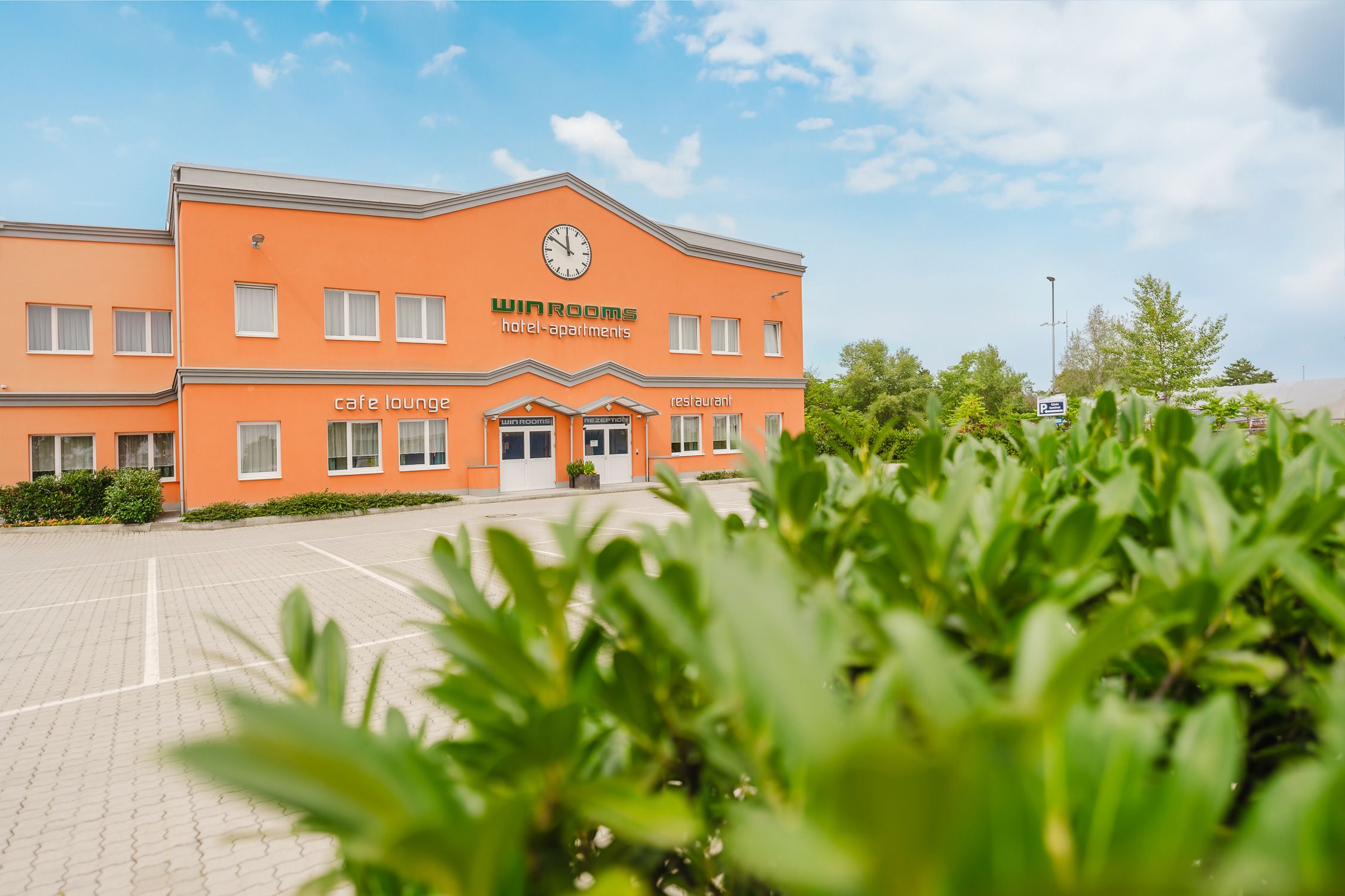 Außenansicht eines orangefarbenen Gebäudes mit der Aufschrift 'Win Rooms hotel-apartments'.