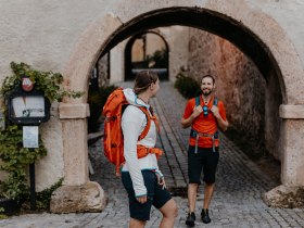 Zwei Wanderer stehen am Eingangstor zum Schloss Gloggnitz