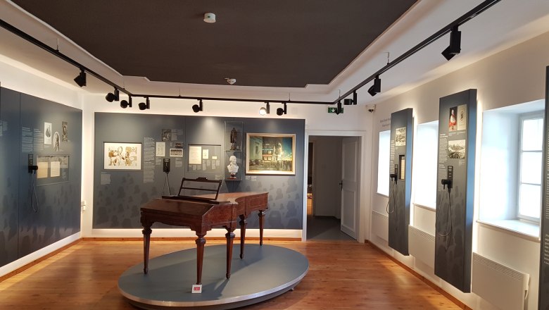 Ausstellungsraum im Haydn-Geburtshaus mit historischem Klavier und Infotafeln.