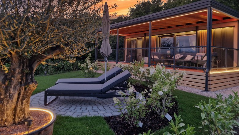 Johannesbachklamm Chalet, © Johannesbachklamm Chalet Ein modernes Chalet mit Terrasse und Liegestühlen im Garten bei Sonnenuntergang.