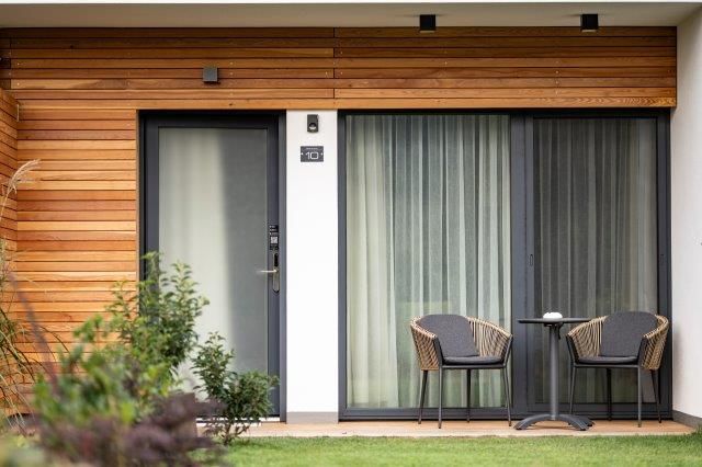 Moderne Terrasse mit zwei Stühlen und einem Tisch vor einem Gästehaus.