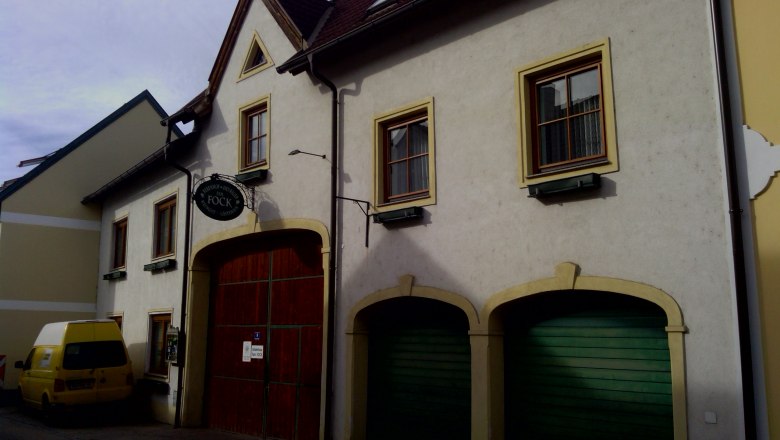 Au&szlig;enansicht eines Geb&auml;udes mit gelbem Van und gr&uuml;nen Garagentoren.