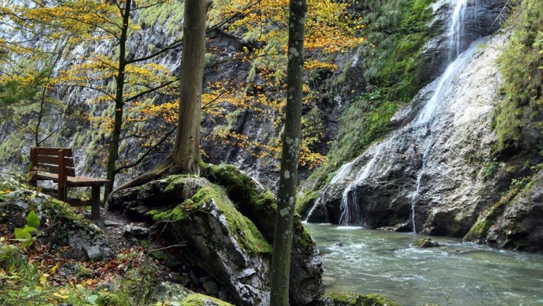 Bank am Fluss im Naturpark &Ouml;tscher Torm&auml;uer mit Wasserfall und herbstlichen B&auml;umen.