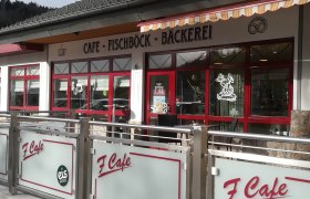 Außenansicht eines Cafés mit rotem Rahmen und Beschriftung 'Café Fischböck Bäckerei'.