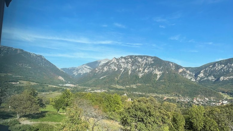 Blick auf eine Berglandschaft mit blauem Himmel und gr&uuml;nen Wiesen.