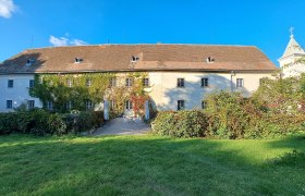 Schloss Poysbrunn mit bewachsener Fassade und Garten.
