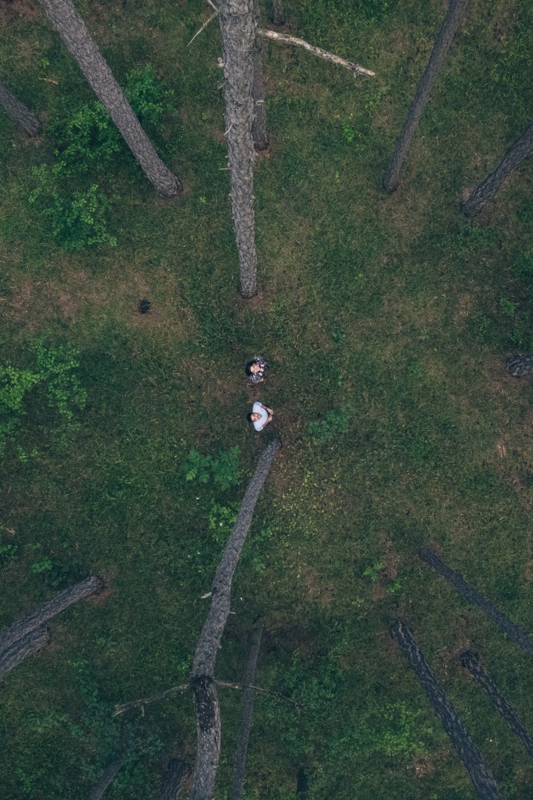 Zwei Personen von oben stehen mitten im Wald