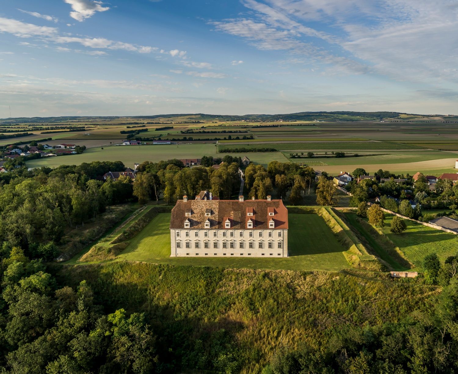 Luftaufnahme von Schloss Stetteldorf am Wagram umgeben von grüner Landschaft und Feldern.