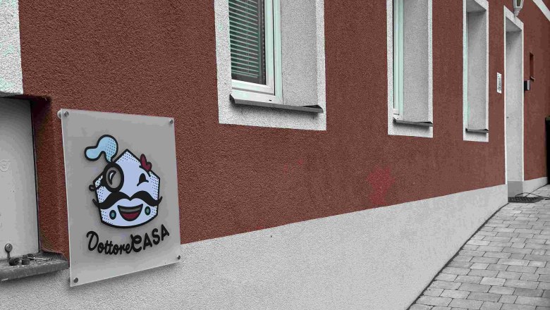 Außenansicht eines Gebäudes mit roter Fassade und einem Schild mit der Aufschrift 'Dottore Casa'.