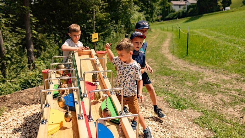 Kinder spielen an einer Kugelbahn im Freien.