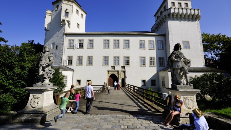 Schloss Asparn/Zaya mit Besuchern und Statuen im Vordergrund.