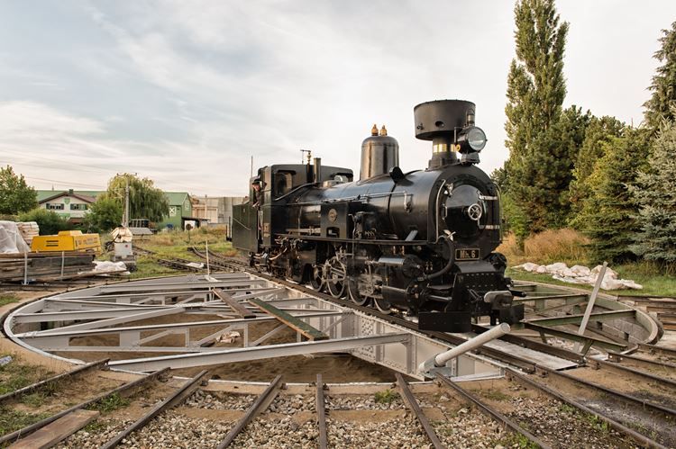 Eine schwarze Dampflok auf einer Drehscheibe im Freien.