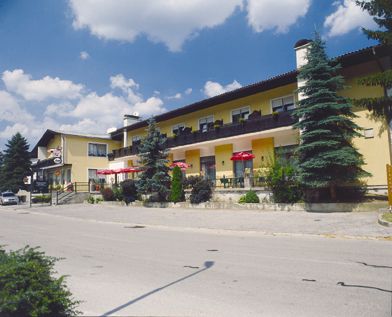 Gelbes Gebäude mit Café und Restaurant, umgeben von Bäumen, unter blauem Himmel.