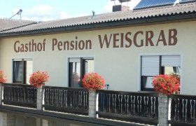 Fassade der Pension Weisgrab mit Blumenkästen auf dem Balkon.