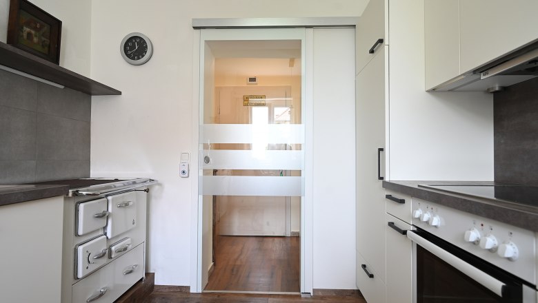 Moderne K&uuml;che mit Herd, Schr&auml;nken und Glast&uuml;r.