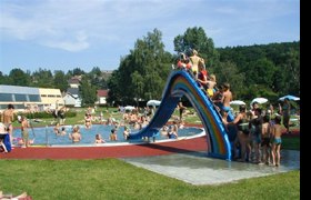 Kinder spielen auf einer bunten Rutsche im Freibad.