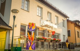 Au&szlig;enansicht eines Caf&eacute;s mit Terrasse und bunter Blumendekoration.