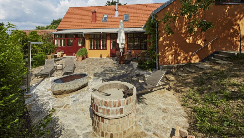 Terrasse einer Villa mit Liegest&uuml;hlen und Feuerstelle.