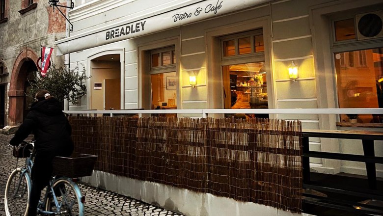 Au&szlig;enansicht eines Caf&eacute;s mit einem Radfahrer auf Kopfsteinpflaster.