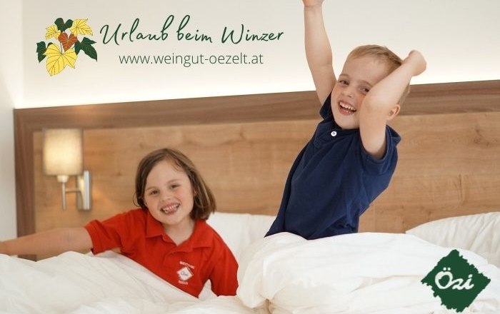 Zwei Kinder spielen fröhlich in einem Bett in einem Gästezimmer.