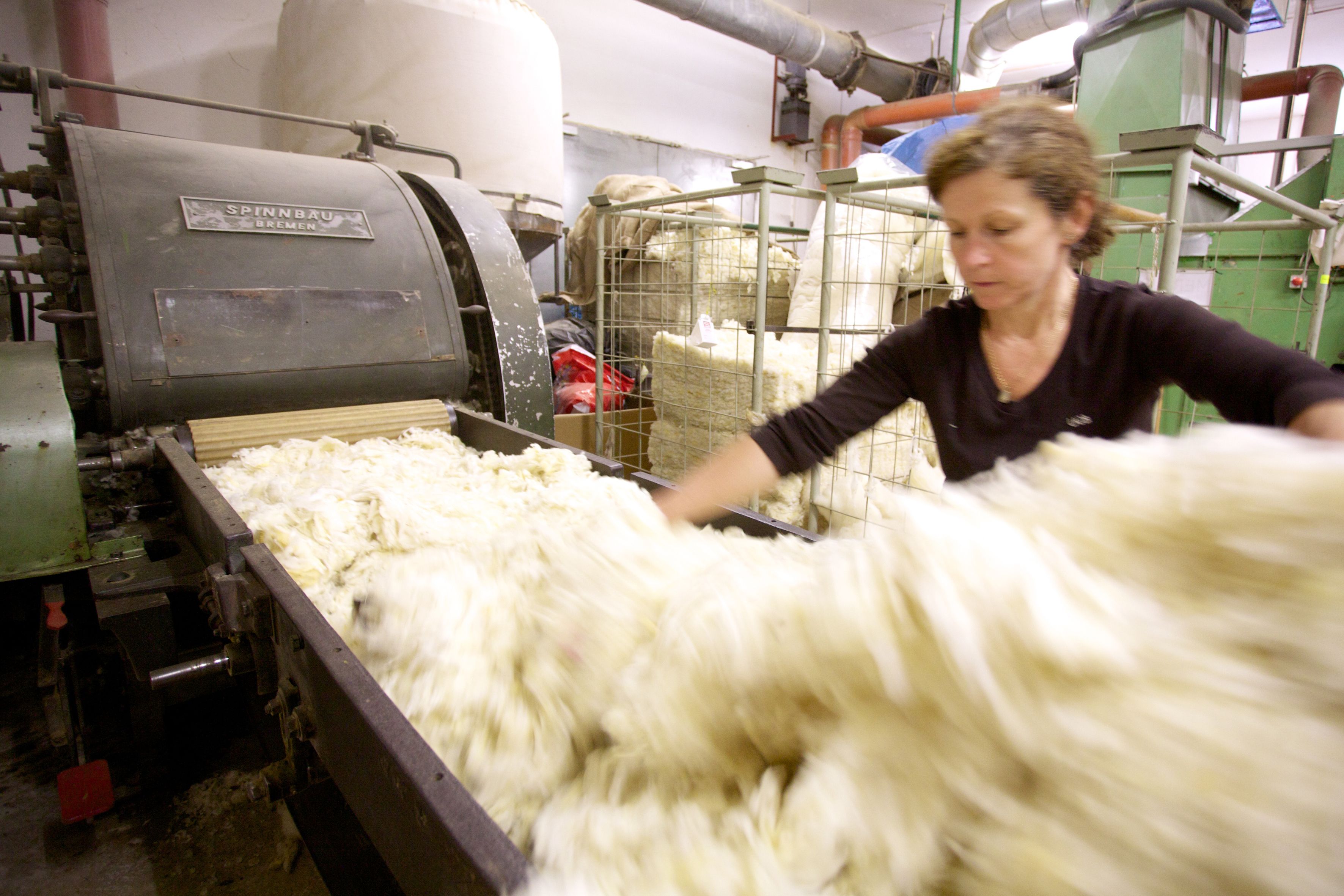 Frau arbeitet in einer Wollwerkstatt an einer Maschine.