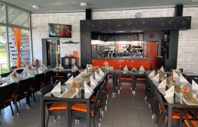 Ein stilvoll eingerichtetes Café mit gedeckten Tischen und einer Bar im Hintergrund.