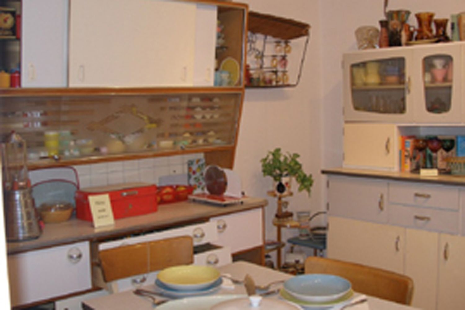 Innenansicht eines Küchenmuseums mit Retro-Möbeln und Geschirr.