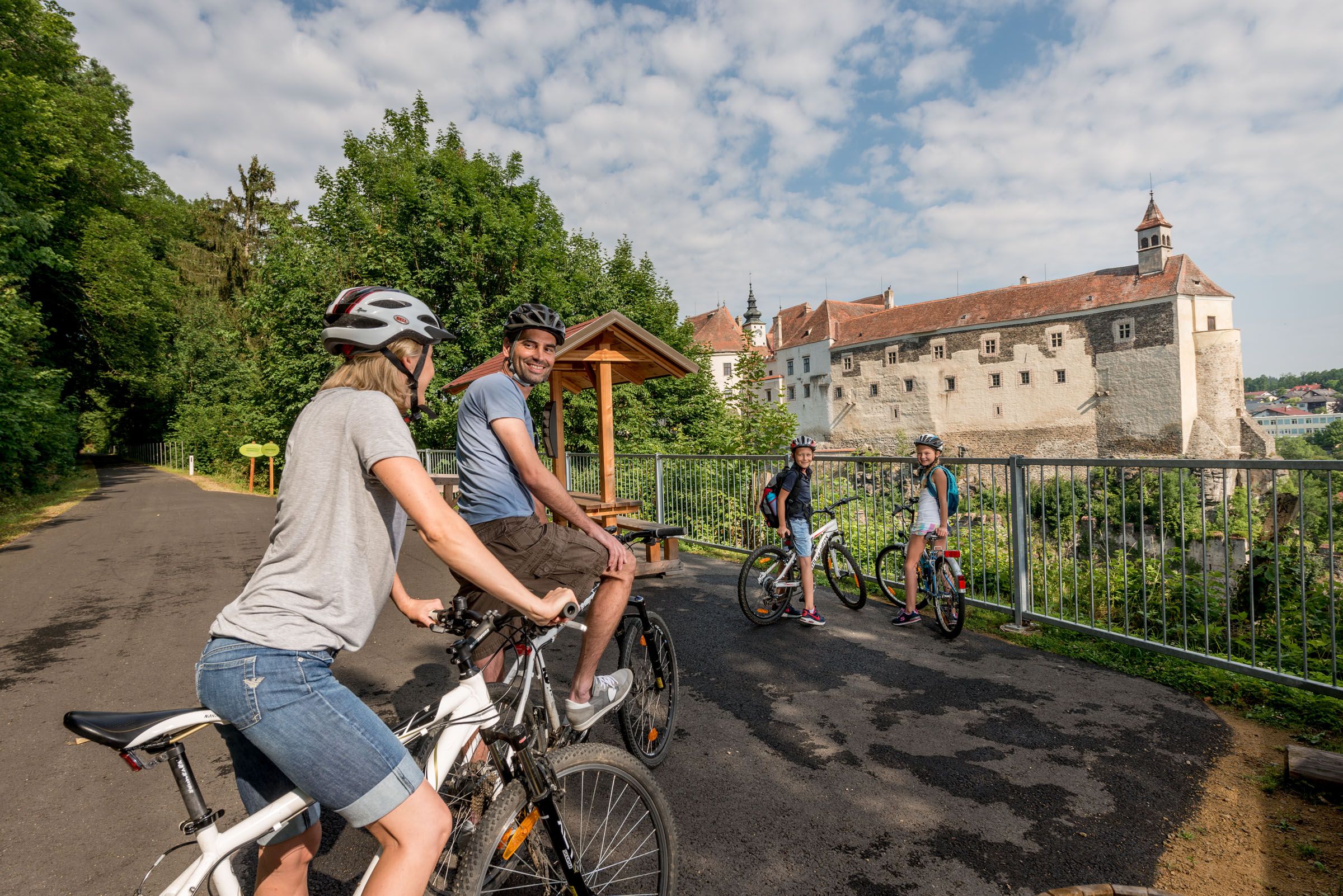 Vier Radfahrer auf einem Weg mit einem Schloss im Hintergrund.