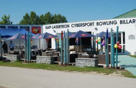 Au&szlig;enansicht eines Freizeitzentrums mit Schirmen und Sitzgelegenheiten.