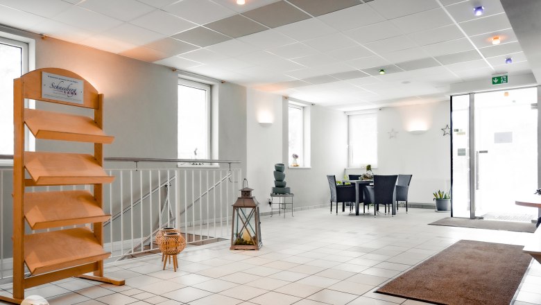 Heller Empfangsbereich mit Tisch, Stühlen und Dekoration.